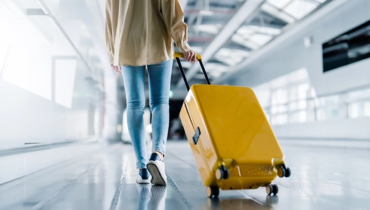Wielkanoc 2024 samolotem, kobieta z żółtą walizką na lotnisku