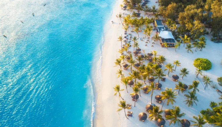 Zanzibar we wrześniu, widok na plażę z palmami i parasolami, błękitna woda