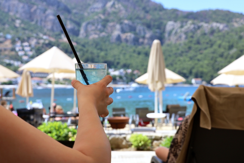 Kobieta trzyma drinka podczas relaksu z widokiem na basen i góry.