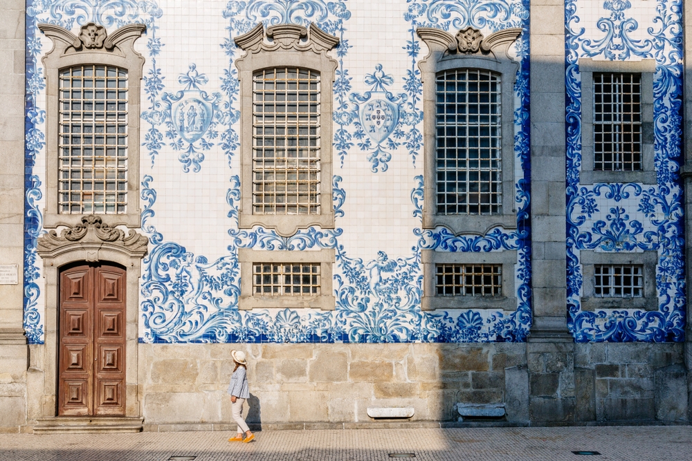 City break – 6 powodów, aby wybrać hotele miejskie podczas kilkudniowych wakacji 7 Kobieta spacerująca pod budynkiem z mozaiką w Porto.