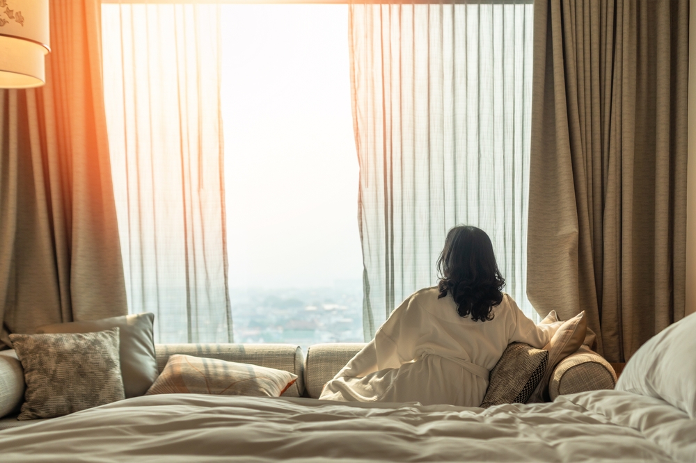 City break – 6 powodów, aby wybrać hotele miejskie podczas kilkudniowych wakacji 6 Kobieta odpoczywająca w pokoju hotelowym po zwiedzaniu miasta.